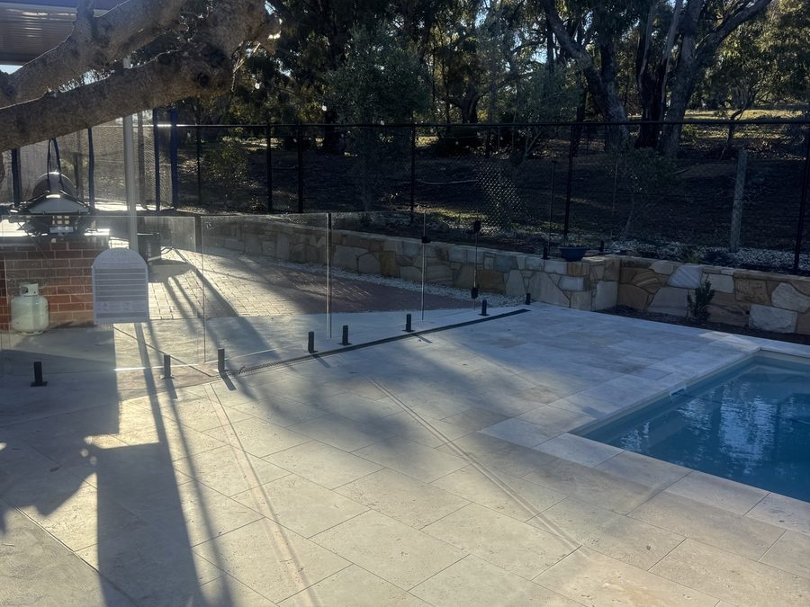 Glass pool barrier beneath the overhanging limb of a large gum tree
