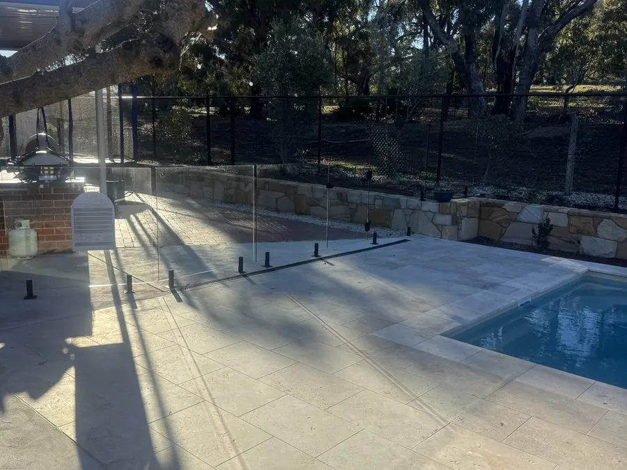 Glass pool barrier beneath the overhanging limb of a large gum tree