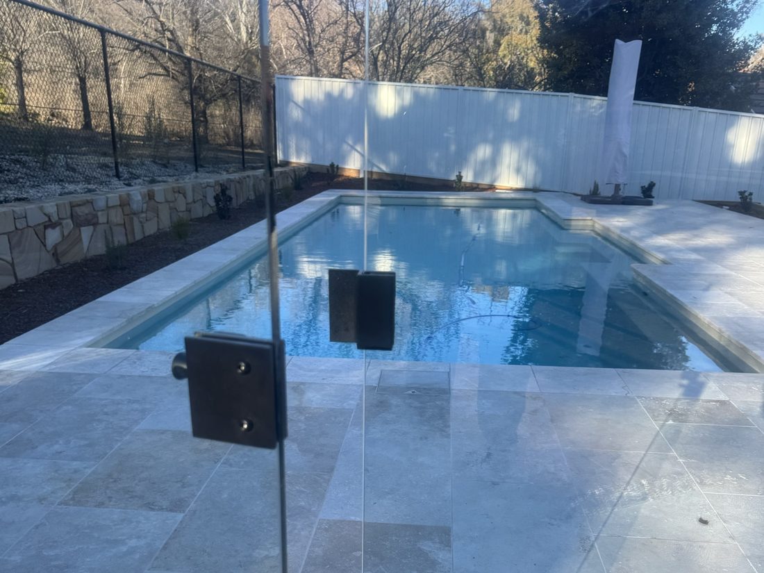 Glass pool gate on pivot hinges beside a lap pool